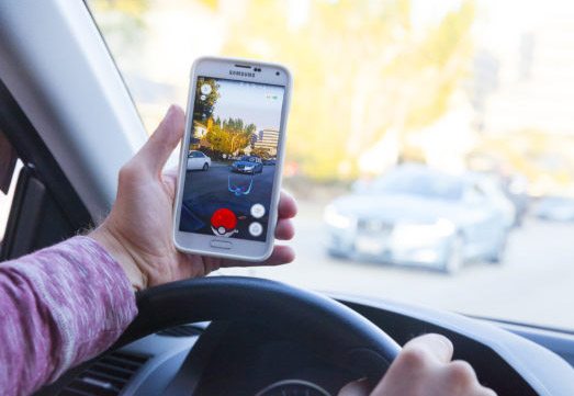 Playing Pokemon Go While Driving Distracted Man Holding Smartphone in Car - Distracted Driver Accident Lawyer in California - Johnson Attorneys Group