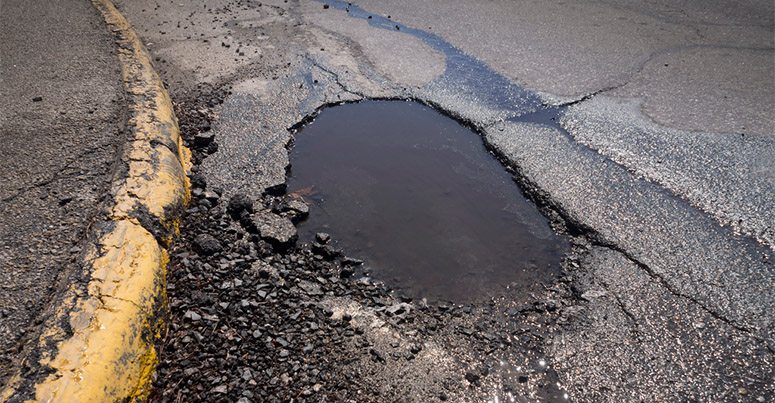 Pot Hole Wet Asphalt with Cracked Gravel - Unsafe Road Conditions in California - Johnson Attorneys Group